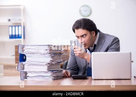 Junge männliche Mitarbeiter mit übermäßiger Arbeit unzufrieden Stockfoto