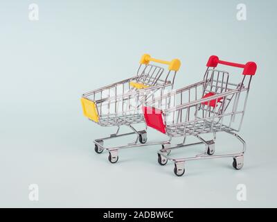 Zwei kleine Einkaufswagen auf blauem Hintergrund. Leerzeichen für Text Stockfoto