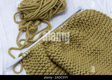 Stricken Pullover mit Merino Wolle Garn und mit einem Stricken nähen. Auf einem grauen Holz Oberfläche Stockfoto