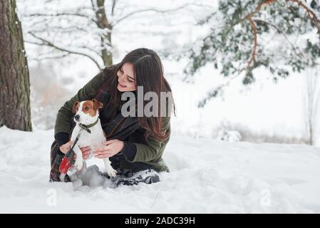 Smiling brunette Spaß beim Spaziergang mit ihrem Hund im Winter Park Stockfoto