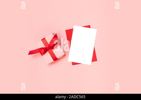 Geschenkbox in rosa Papier mit roter Schleife verpackt, leeren roten Umschlag Vorlage auf einem rosa Hintergrund Stockfoto