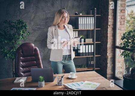 Foto von Ernst zuversichtlich konzentriert ceo konzentrierte sich auf die Überprüfung von Berichten von ihren Arbeitnehmern stehend am Tisch mit Diagrammen über es Stockfoto