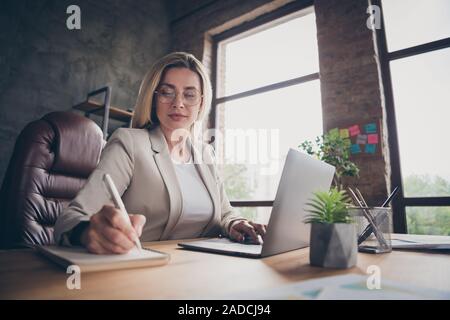 Tief unter dem Blickwinkel - Foto von schweren konzentrierte sich Frau unter Hinweis auf den Vergleich der Daten über Laptop mit Daten im Notebook Stockfoto