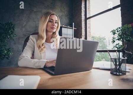 Tief unter dem Winkel Foto anzeigen fröhliche, schöne Blonde Unternehmer sitzen am Desktop mit Notebook und Notepad auf mit Diagrammen Analyse der jährlichen Stockfoto