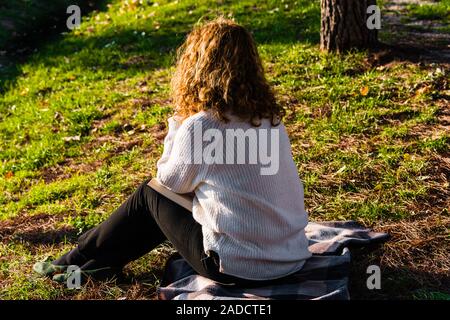 Blonde und lockig behaarte Frau liest im Park Stockfoto