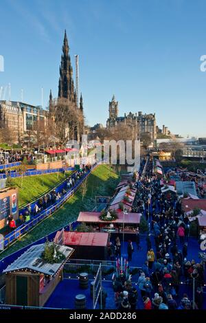 Menschenmassen in Edinburgh Weihnachtsmarkt. Walter Scott Monument und Balmoral Hotel im Hintergrund. Die Princes Street Gardens. Edinburgh, Schottland Stockfoto