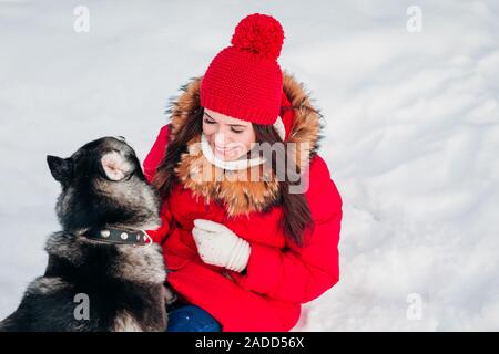 Attraktive junge Frau mit Spaß draußen im Schnee mit ihr Hund Stockfoto