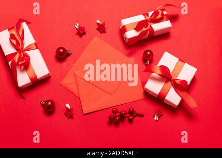 Zwei roten Umschlag mit Weihnachtsdekor, Geschenke Boxen auf einem roten Hintergrund. Flach, Ansicht von oben, kopieren. Stockfoto