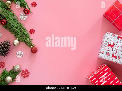 Green Pine, Pine Cone, Schneeflocken, Weihnachtsschmuck und Geschenkverpackung Geschenkpapier in Rot auf rosa Hintergrund mit Kopie Raum Stockfoto