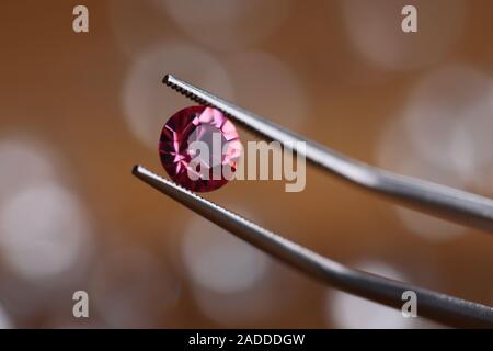 Juwelier in Werkstatt hält rosa Stein in Pinzette Stockfoto