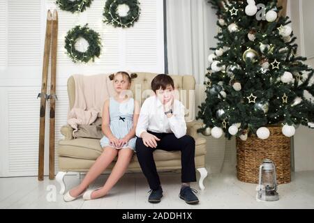 Die Gefolterten Bruder und Schwester Sitzen auf der Couch von der Weihnachtsbaum Stockfoto