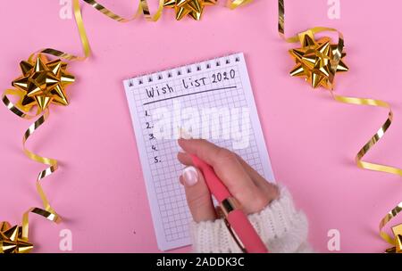 Woman's Hand schreiben in Leer Notebook mit Weihnachtsschmuck auf dem Hintergrund eingerichtet. Ansicht von oben, flach, kopieren Raum Stockfoto