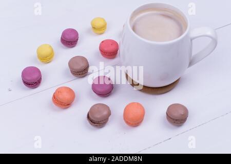 Weiße Tasse duftenden Cappuccino mit Makkaroni Kuchen auf weißem Hintergrund, Ansicht von oben Stockfoto