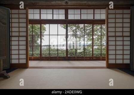 Blick auf grüne Bäume und Kyoto von einem Fenster in ein traditionelles Zimmer mit Shoji Teiler und Tatami in Honen-in Tempel Stockfoto