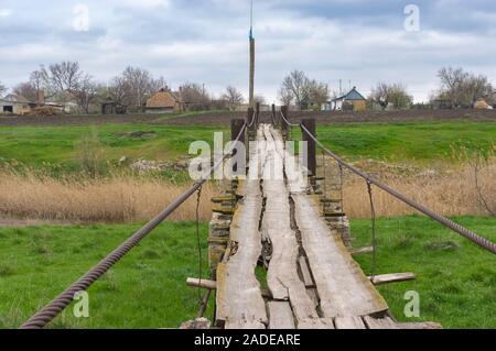 Fußgängerzone alte Holz- Fuß-Brücke über den kleinen Fluss Topyla Tomakivka im Dorf, zentral Ukraine Stockfoto