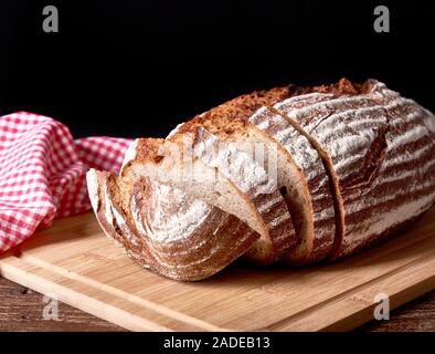 Stillleben mit gebackenen geschnittenes Brot Brot. Rot Geschirrtuch auf schwarzem Hintergrund isoliert. Stockfoto