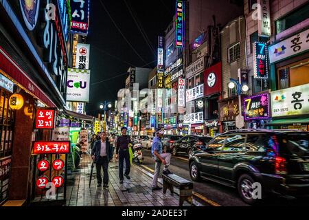 Busan, Korea, 1. Oktober 2019: eine belebte Straße in der Nacht Busan mit Menschen Verkehr und beleuchteten Restaurants und Geschäften Schilder in Busan, Südkorea Stockfoto