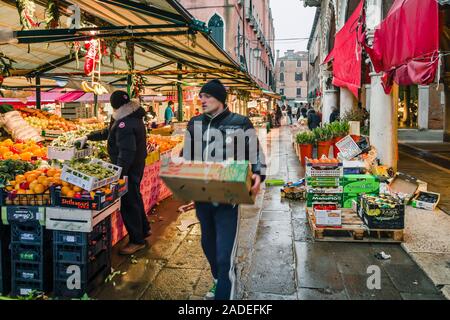 Venedig, Italien - 24. Dezember 2012. Der Händler trägt Kisten mit Gemüse zu einem traditionellen europäischen Börse zu den Mercato di Rialto, Veni Abschaltdruck Stockfoto