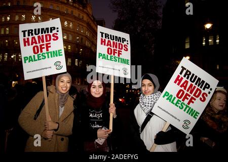 3. Dezember 2019 Trafalgar Square. Anti Trump Demonstration. Drei junge Frau halten Plakate mit der Aufschrift "Trump Hände weg von Palästina;". Stockfoto