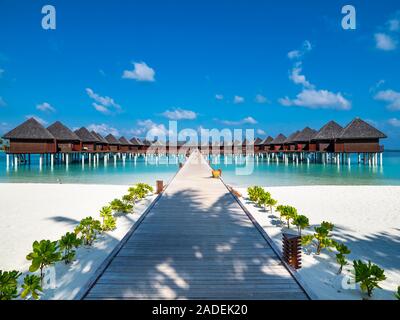 Über flache Wasser Fußgängerbrücke zum Wasser Bungalows, Insel in Süd Male Atoll, Malediven Stockfoto