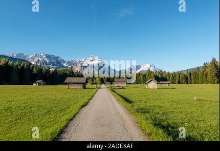 Scheunen in einer Wiese, Ehrwalder Sonnenspitz und Bergen, in der Nähe von Ehrwald, Tirol, Österreich Stockfoto