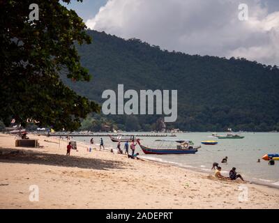 Batu Ferringhi Beach, Malaysia - November 2019: Touristen in weißen sandigen Küste Boote und Jetskis bewölkten Tag im asiatischen Inseln Stockfoto