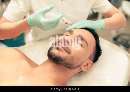 Hände der professionelle Kosmetiker die Injektion an der Stirn Stockfoto