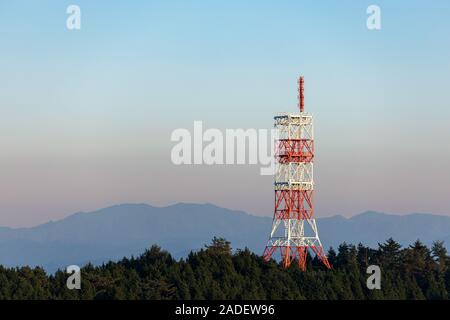 Rote und weiße Antenne Tower auf der schönen bewaldeten Berggipfel bei Sonnenuntergang Stockfoto