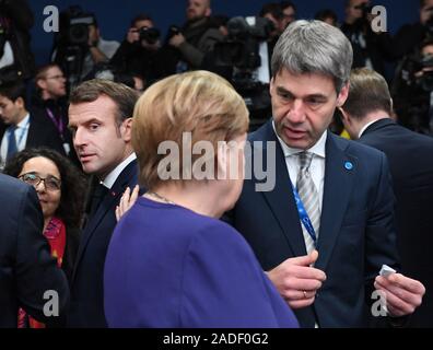Der französische Präsident Emmanuel Längestrich (links) dreht sich mit Bundeskanzlerin Angela Merkel, während der jährlichen Nato-Gipfel der Staats- und Regierungschefs im Grove Hotel in Watford, Hertfordshire zu schauen. Stockfoto