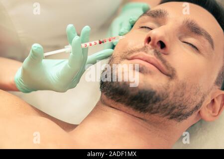 Hand mit Spritze, Injektion in die Gesichtshaut Stockfoto