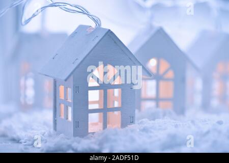 Weihnachten und neues Jahr Hintergrund mit einer Girlande in Form von kleinen Häusern auf dem Schnee Stockfoto