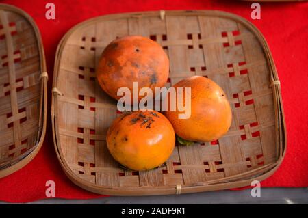 Persimone Früchte in Bambus Korb im ländlichen Markt von Kyoto, Japan. Stockfoto