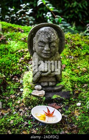 Statuen von lächelnden Jizo Bosatsu mit grünem Moos im Zen Garten in Sanzen-in Tempel, Kyoto, Japan. Stockfoto