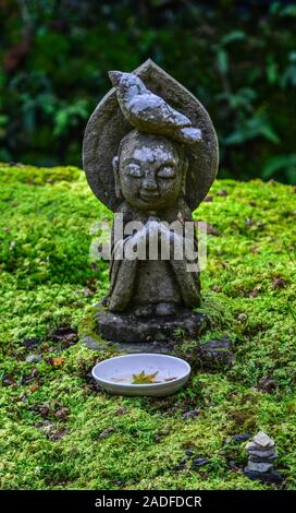 Statuen von lächelnden Jizo Bosatsu mit grünem Moos im Zen Garten in Sanzen-in Tempel, Kyoto, Japan. Stockfoto