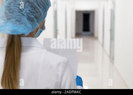 Ärztin in der medizinischen Verschleiß auf Analyse Ergebnisse über leere medizinische Korridor Stockfoto