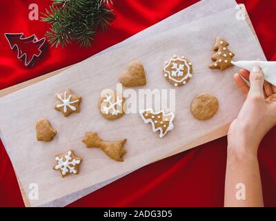 Weihnachtsbäckerei. Man dekorieren frisch gebackene Lebkuchen Plätzchen mit Puderzucker und Süßwaren-Dichtmasse. Festliche Essen, Familie kulinarisch, Weihnachten und Stockfoto