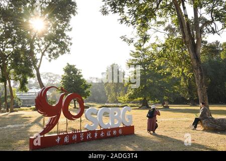 Guangzhou, Guangdong Provinz Chinas. 3. Dezember, 2019. Ein Besucher stellt für Fotos neben einem Denkmal markiert das 90-jährige Jubiläum der Südchinesische Botanische Garten in Guangzhou, Provinz Guangdong im Süden Chinas, Dez. 3, 2019. Credit: Deng Hua/Xinhua/Alamy leben Nachrichten Stockfoto