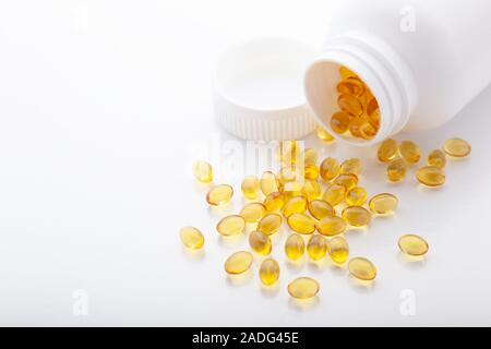 Ansicht von oben in Gold Fischöl aus pilleflasche verstreut für gute Gesundheit auf weißem Hintergrund. Zusätzliche Nahrung. Omega 3. Vitamin-E-Kapseln sa Stockfoto