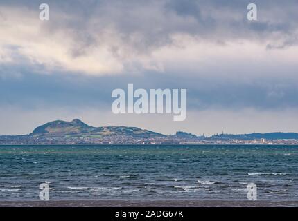 Longniddry Bents, East Lothian, Schottland, Großbritannien, 4. Dezember 2019. Wetter in Großbritannien: An einem windigen Tag breitet sich ein dunkler, bedrohlicher Himmel über der Skyline von Edinburgh aus, wobei Arthur's Seat, Edinburgh Castle, Calton Hill-Denkmäler und die hohen Kraniche der Umbauarbeiten sichtbar sind. Blick von den Longniddry Bents über den Firth fo Forth Stockfoto