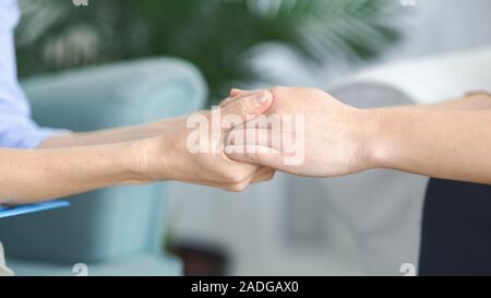 Eine Frau, die andere Frau Hände in unterstützende Geste Stockfoto