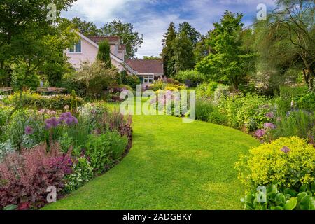 Blick auf abfallenden Garten mit Wicklung Blumenrabatten. Stockfoto