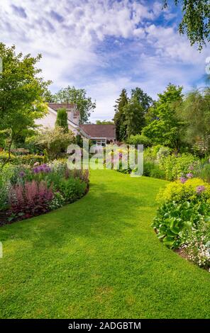 Blick auf abfallenden Garten mit Wicklung Blumenrabatten. Stockfoto