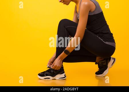 Nicht erkennbare African American Girl Schnürung Schuhe auf gelbem Hintergrund Stockfoto