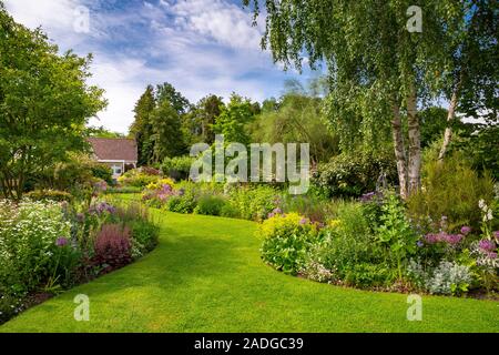 Blick auf abfallenden Garten mit Wicklung Blumenrabatten. Stockfoto