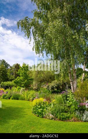 Blick auf abfallenden Garten mit Wicklung Blumenrabatten. Stockfoto