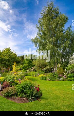 Blick auf abfallenden Garten mit Wicklung Blumenrabatten. Stockfoto