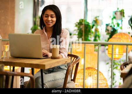 Dunkelhaarige Student in legere Kleidung Arbeiten auf Ihrem Laptop Stockfoto