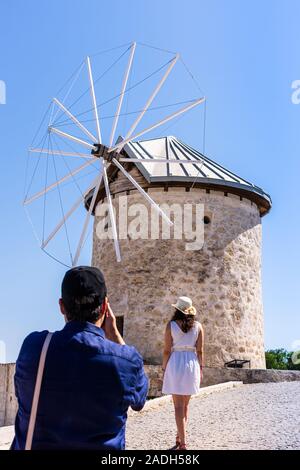 Alacati, Cesme, İzmir / Türkei-Juni 23,2019: Eine Frau in Weiß beobachtet die Windmühlen. Er wird gerade fotografiert. Stockfoto