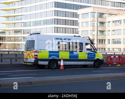 London, Großbritannien. 4. Dez, 2019. Die Menschen weiterhin ihren Respekt auf die London Bridge zu fünf Tage nach dem Terroranschlag von Usman Khan zahlen. Die Menschen stehen und schauen Sie auf die Blumen, es gibt noch eine polizeiliche Präsenz und Zelte errichtet, den Tatort zu bewahren. Credit: Keith Larby/Alamy leben Nachrichten Stockfoto