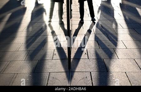 Stuttgart, Deutschland. 04 Dez, 2019. Passanten werden in einem Schaufenster wider, wenn die Sonne niedrig ist. Credit: Marijan Murat/dpa/Alamy leben Nachrichten Stockfoto